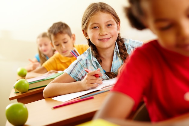 Smiling girl with an apple on her desk