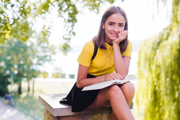 Smiling girl with book in park