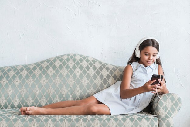 Smiling girl with headphone on her head looking at mobile phone