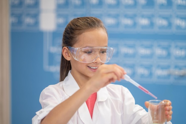 Smiling girl with pipette and test tube