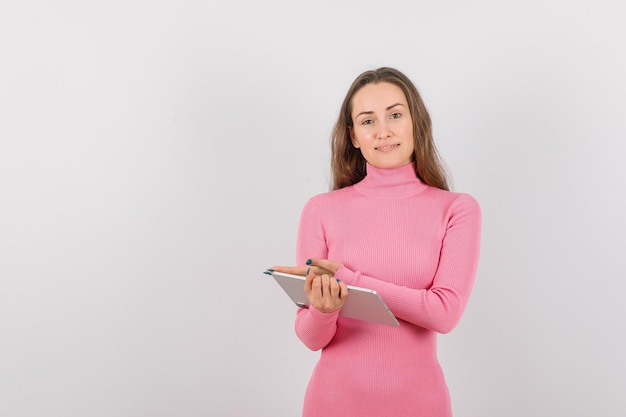 Smiling girl with planshet computer is pointing to left with hand on white background