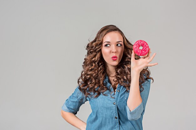 The smiling girl with round cake on gray  wall. Long hair.