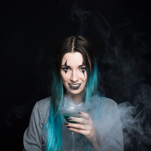 Smiling girl with spooky makeup holding wineglass