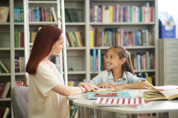 Free photo smiling girl and woman sitting at table