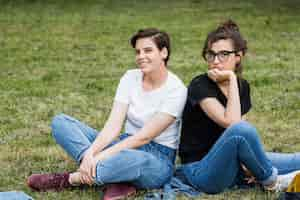 Free photo smiling girls friends sitting on park grass