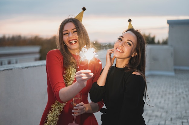 Smiling girls holding the sparklers on the rooftop