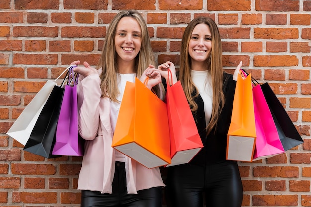 Smiling girls looking at camera while holding shopping bags