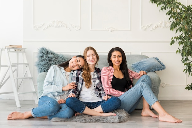 Foto gratuita ragazze sorridenti che si siedono sul pavimento con le gambe attraversate a piedi nudi