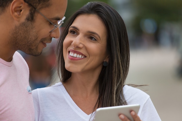 Smiling good friends with tablet on street