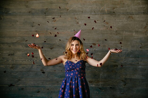 Smiling gorgeous woman celebrating a holiday, playing with confetti