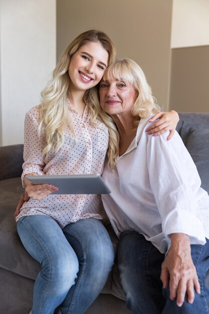 Smiling grandmother and her granddaughter holding a tablet