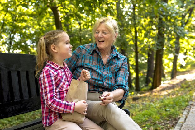 Smiling grandmother sitting on a bench with her female grandchild in the park