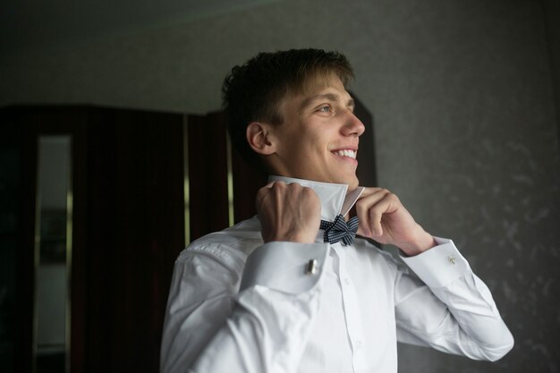 Smiling groom adjusting his bow tie
