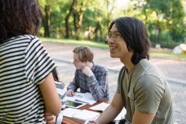 座っていると勉強している若い学生の笑顔のグループ