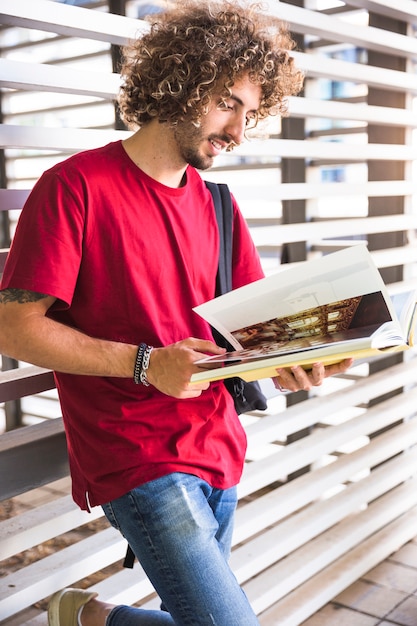 Smiling guy turning pages of textbook