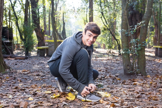 Smiling guy tying laces of trainers before training