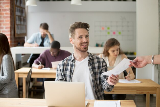 Smiling handsome entrepreneur giving financial document to coworker. 