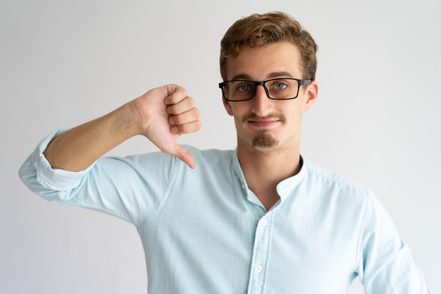 Smiling handsome guy in glasses expressing disapproval.