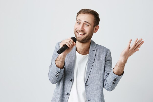 Smiling handsome man singing karaoke with microphone
