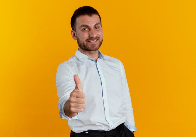 Smiling handsome man thumbs up isolated on orange wall