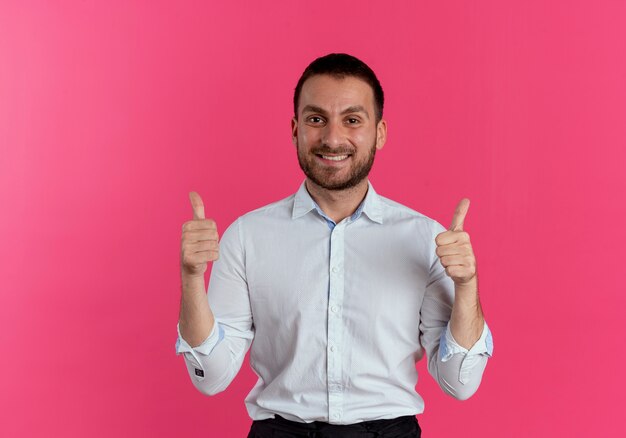 Smiling handsome man thumbs up with two hands isolated on pink wall