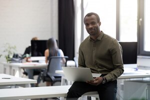 Smiling happy afro american businessman sitting on his desk