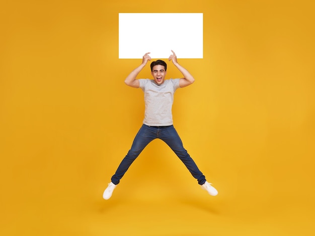 노란색 배경에 빈 말풍선을 들고 점프하는 행복한 아시아 남성이 발표 개념을 광고합니다.