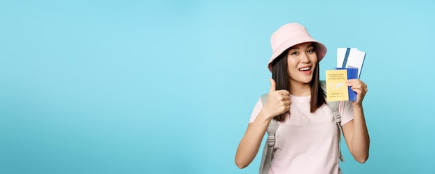 Free photo smiling happy asian tourist girl shows thumbs up and international vaccination certificate vaccine p