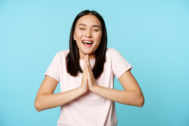 웃고 있는 행복한 아시아 여성은 나마스테의 구걸 제스처를 보여주고 소원을 빌어주는 무언가를 꿈꾸고 있습니다...