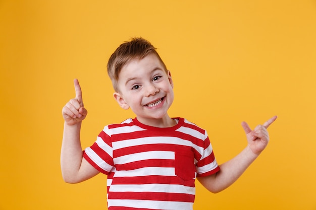 Улыбающийся счастливый мальчик, указывая пальцем на copyspace