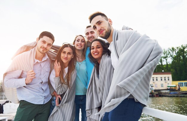 Smiling happy group of friends outdoors on the beach pier.