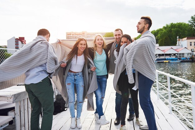 Smiling happy group of friends posing outdoors on the beach pier.