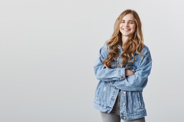 Smiling happy pleased girl in denim jacket with arms crossed