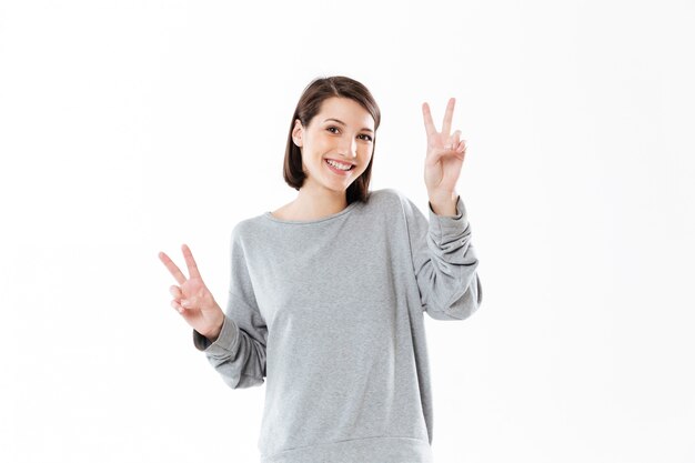 Улыбается счастливая женщина, показывая мирный жест двумя руками
