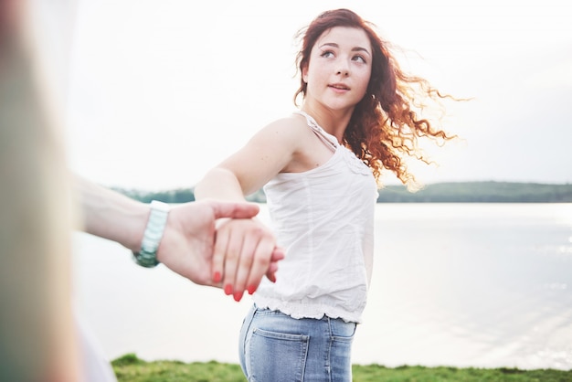 A smiling happy woman with a playful expression and a hand with her husband.