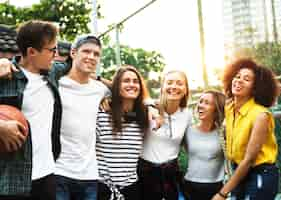 Free photo smiling happy young adult friends arms around shoulder outdoors friendship and connection concept