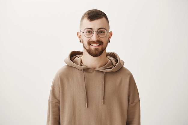 Smiling hipster guy in glasses and hoodie looking happy