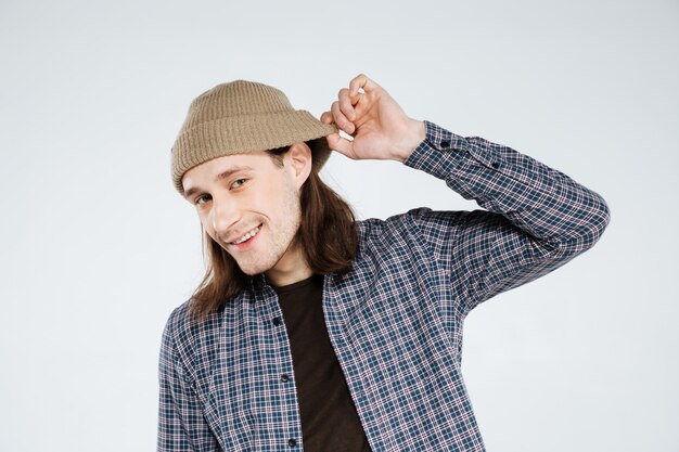 Smiling hipster holding hat and listening