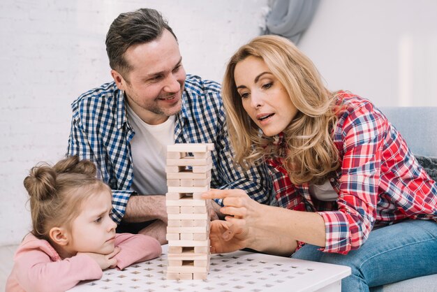 Smiling husband looking their wife while arranging wooden block game tower