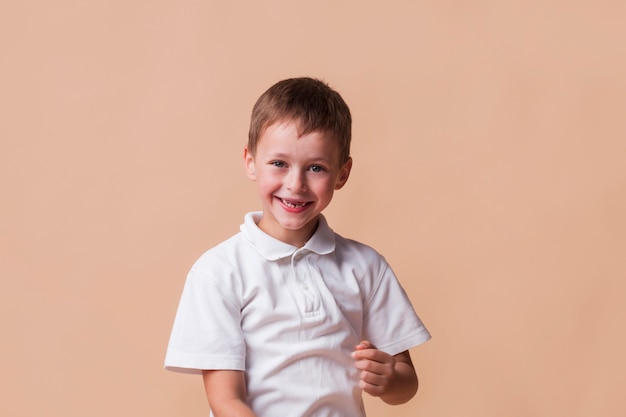 Smiling innocent boy on beige backdrop