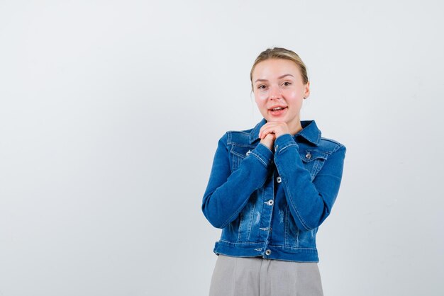 The smiling is putting her clasped hands under chin on white background