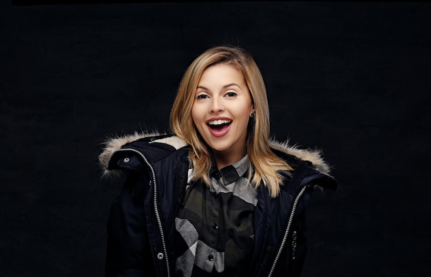 Free photo smiling joyful blonde female in a winter warm jacket with fur hood.