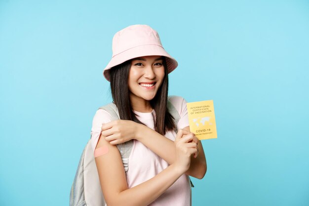 Улыбающаяся корейская туристка счастливая женщина показывает свою вакцинированную руку и международную вакцинацию от COVID ...