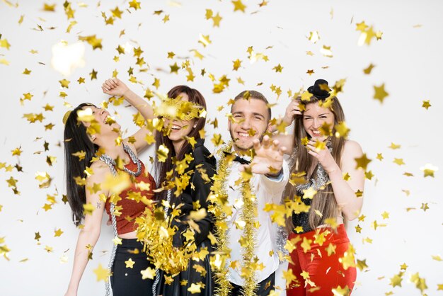 Smiling ladies and guy in evening wear between ornament confetti 