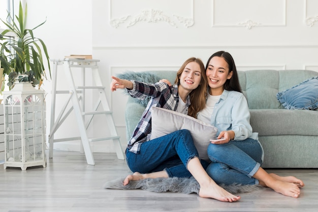 Free photo smiling ladies sitting barefoot on floor