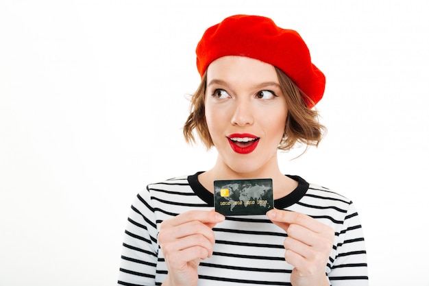 Smiling lady holding credit card and looking aside isolated