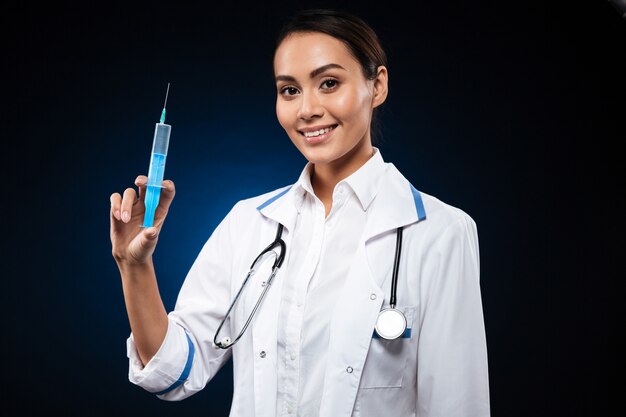 Smiling lady holding syringe and looking