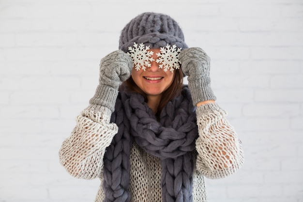 Улыбается женщина в рукавицы, шарф и шляпа с орнаментом снежинки на глазах