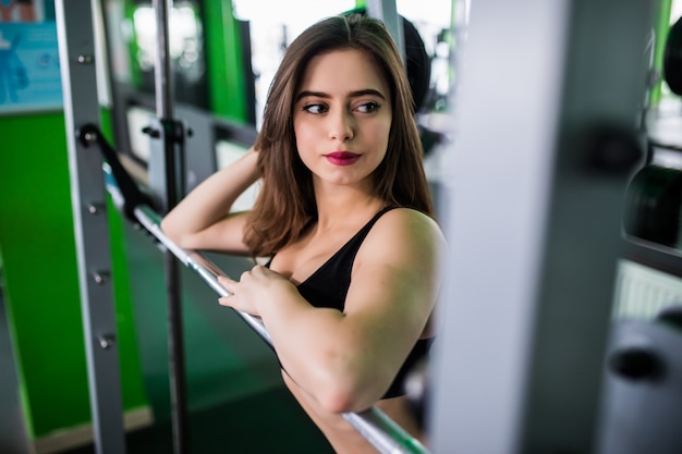 Smiling lady is preparing to make workout with barbell in sportclub