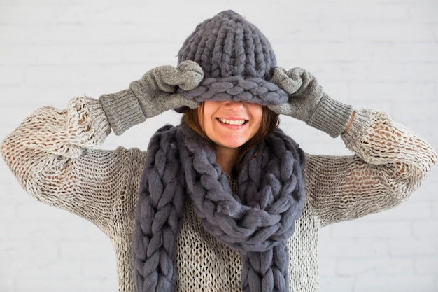 Smiling lady in mittens, scarf and hat on eyes 